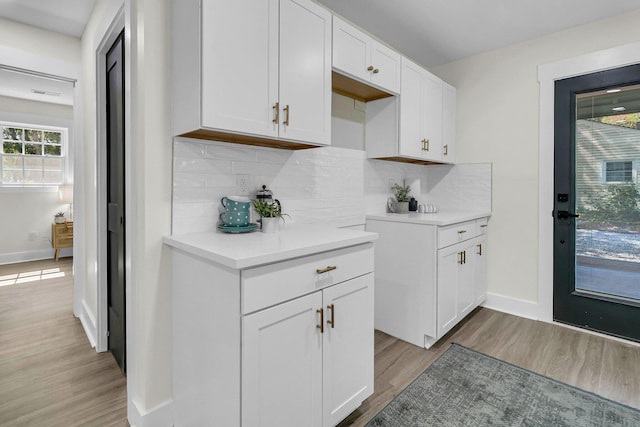 kitchen with decorative backsplash, light wood-type flooring, and white cabinetry