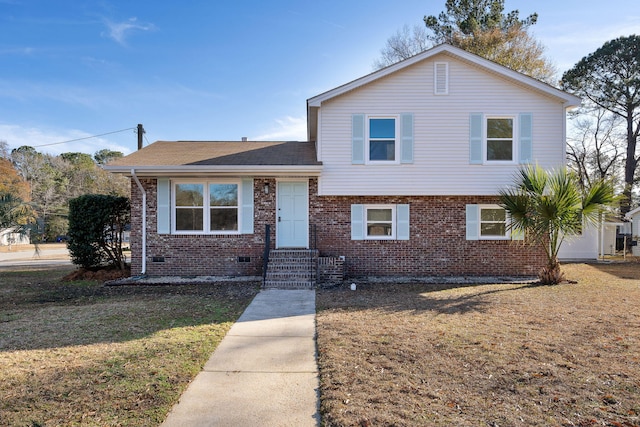 tri-level home with entry steps, brick siding, a front yard, and a shingled roof