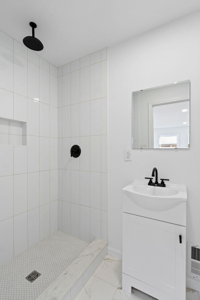 bathroom with tiled shower and vanity