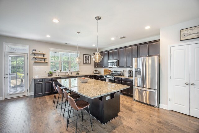 106 Sago Ct, Summerville, SC 29486 - kitchen with appliances with stainless steel finishes, a kitchen breakfast bar, a center island, light stone countertops, and backsplash