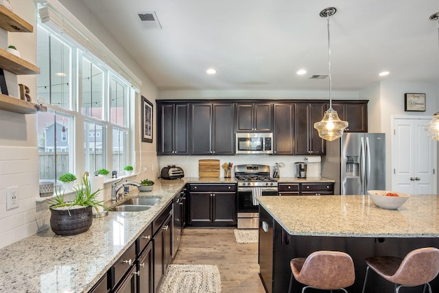 106 Sago Ct, Summerville, SC 29486 - kitchen with appliances with stainless steel finishes, a sink, a breakfast bar, light wood finished floors, and hanging light fixtures