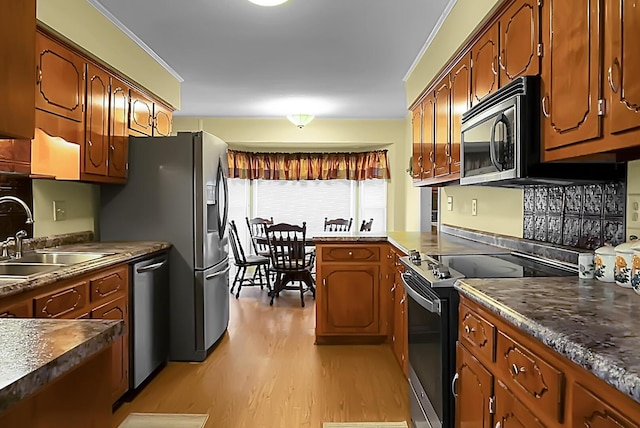 kitchen with sink, light wood-type flooring, ornamental molding, and appliances with stainless steel finishes