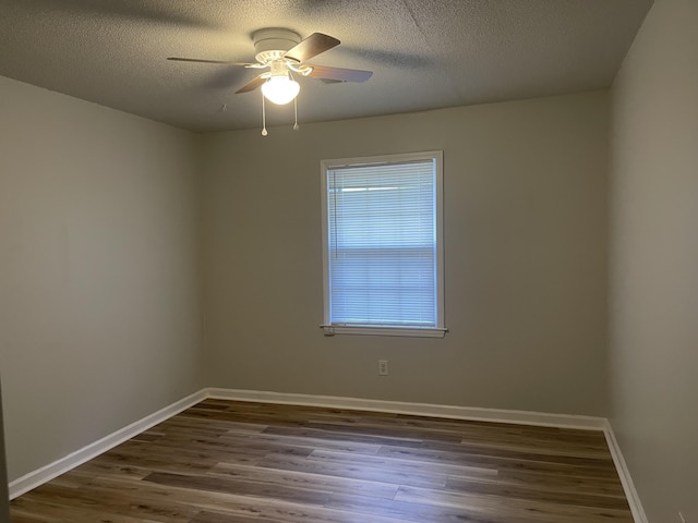 spare room featuring baseboards, wood finished floors, and a textured ceiling