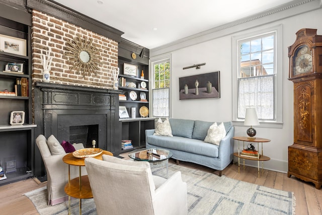 living room featuring baseboards, wood finished floors, a fireplace, and crown molding