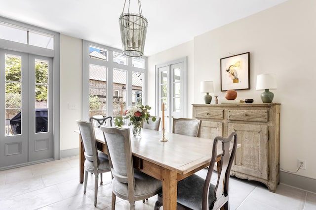 dining space featuring light tile patterned floors, french doors, baseboards, and a notable chandelier