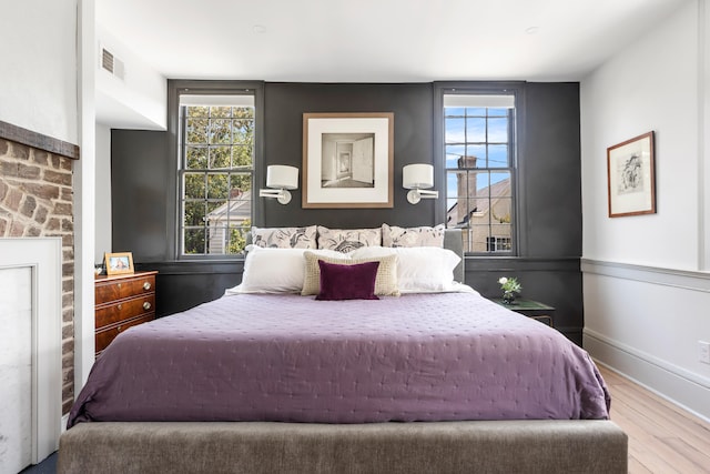 bedroom with wood finished floors, visible vents, and baseboards