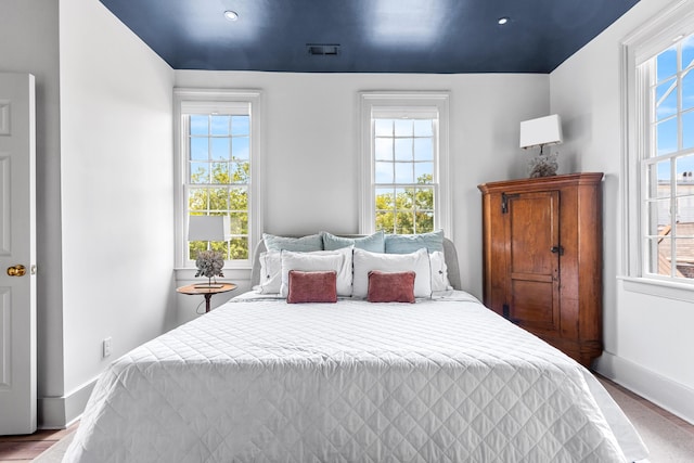 bedroom with visible vents, wood finished floors, and baseboards