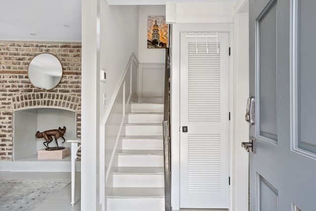 staircase featuring brick wall