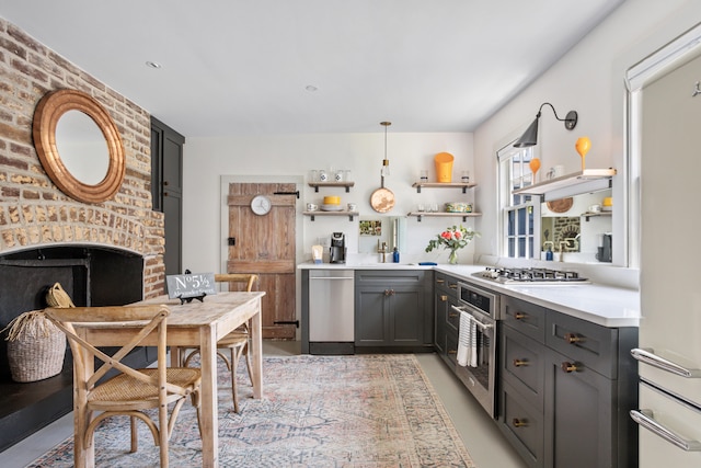 kitchen with open shelves, a fireplace, gray cabinetry, stainless steel appliances, and light countertops