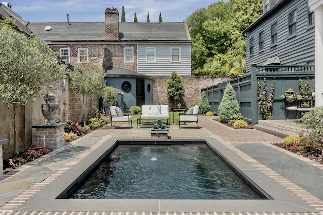 rear view of house featuring a patio, fence, an outdoor living space, a chimney, and brick siding