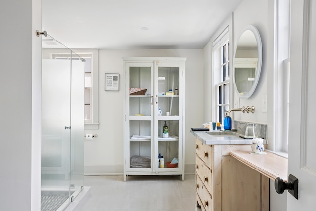 bathroom with a shower with shower door and vanity