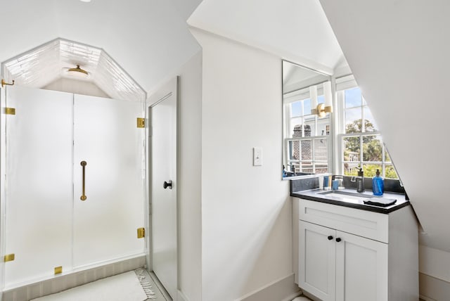 bathroom with a stall shower, vanity, and lofted ceiling