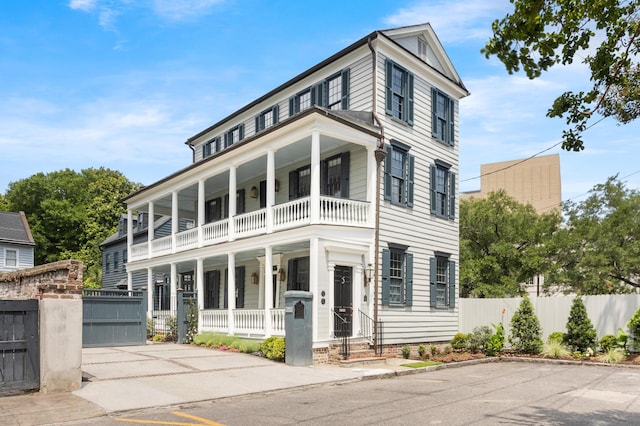 view of front of property with a balcony, a porch, and fence