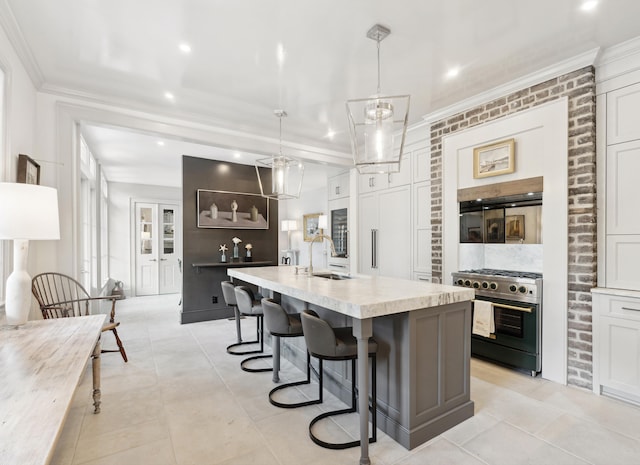 kitchen featuring a sink, high end stove, light countertops, ornamental molding, and a kitchen island with sink