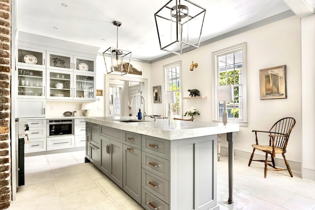 kitchen with a breakfast bar, ornamental molding, gray cabinets, a sink, and white cabinets