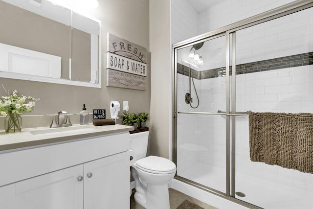 bathroom featuring vanity, toilet, and a shower with shower door