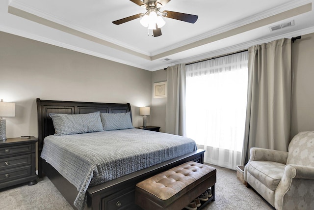 bedroom with ceiling fan, a tray ceiling, light carpet, and multiple windows