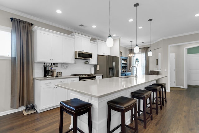 kitchen featuring a kitchen island with sink, sink, stainless steel appliances, and hanging light fixtures