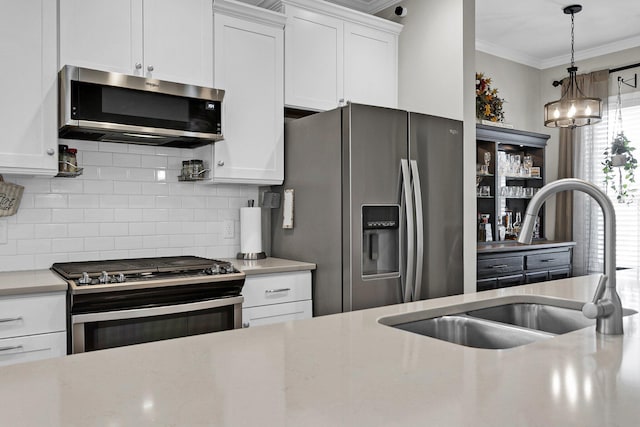 kitchen with sink, tasteful backsplash, ornamental molding, appliances with stainless steel finishes, and white cabinets