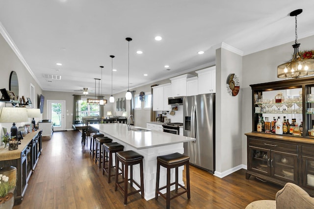 kitchen featuring appliances with stainless steel finishes, decorative light fixtures, sink, a kitchen breakfast bar, and a large island