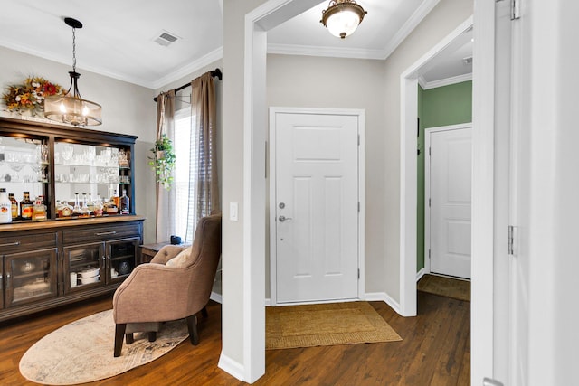 entrance foyer featuring crown molding, dark wood-type flooring, bar, and a notable chandelier