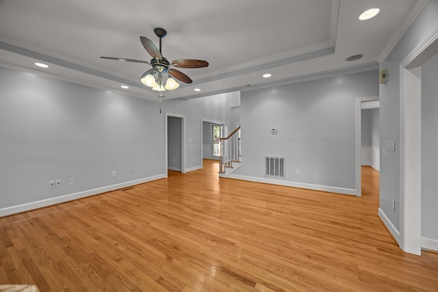 unfurnished living room with a tray ceiling, light hardwood / wood-style flooring, ornamental molding, and ceiling fan