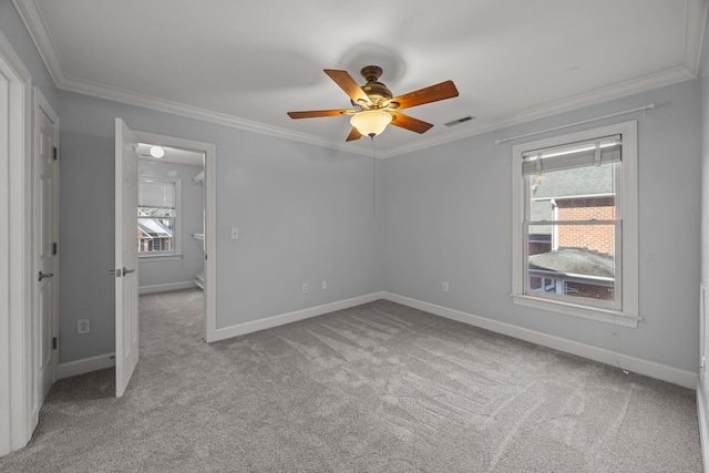 carpeted spare room featuring crown molding, ceiling fan, and a wealth of natural light