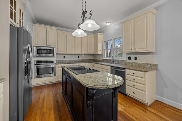 kitchen featuring appliances with stainless steel finishes, decorative light fixtures, sink, a center island, and light stone counters