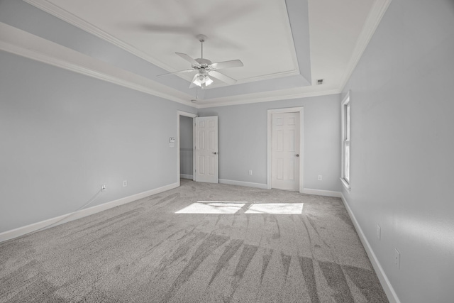 unfurnished bedroom with a tray ceiling, ornamental molding, light colored carpet, and ceiling fan