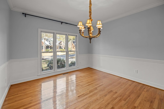 spare room with ornamental molding, light hardwood / wood-style flooring, and a notable chandelier