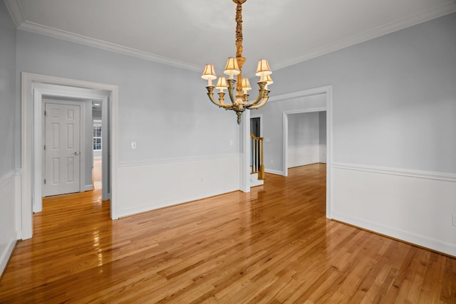 unfurnished dining area with ornamental molding, an inviting chandelier, and light hardwood / wood-style flooring