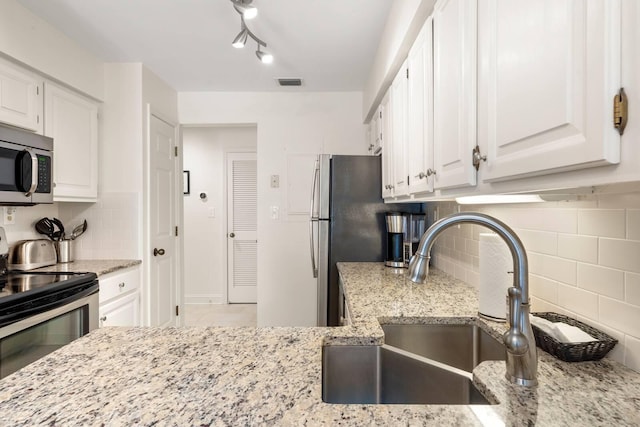 5558 Green Dolphin Way, Kiawah Island, SC 29455 - kitchen with appliances with stainless steel finishes, white cabinetry, decorative backsplash, and light stone counters