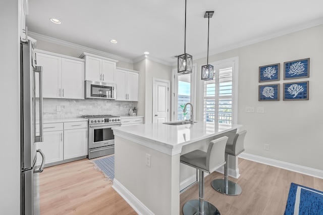 kitchen featuring pendant lighting, sink, white cabinetry, stainless steel appliances, and a center island with sink