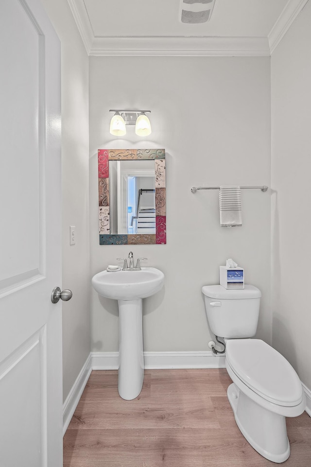 bathroom with crown molding, toilet, and hardwood / wood-style floors