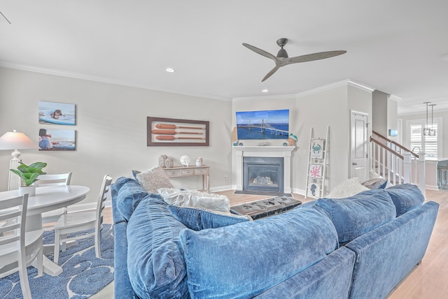 living room with crown molding, ceiling fan, and light wood-type flooring