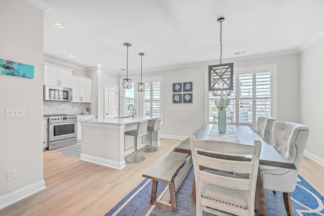 dining room featuring sink, light hardwood / wood-style flooring, and ornamental molding