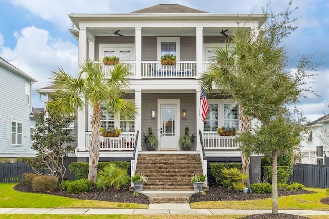 coastal home with a ceiling fan, a porch, a balcony, and fence