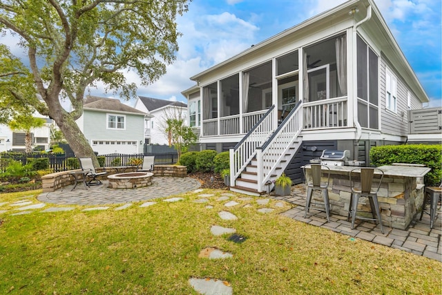 rear view of house with a patio, outdoor dry bar, stairway, an outdoor fire pit, and a sunroom