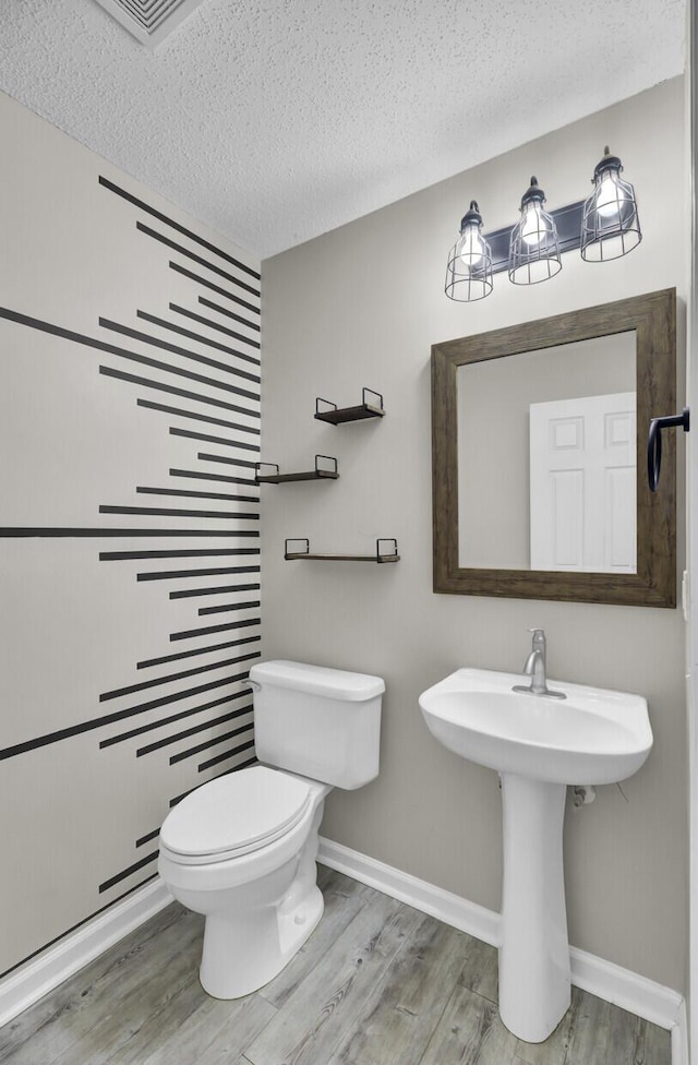 bathroom featuring hardwood / wood-style flooring, toilet, and a textured ceiling