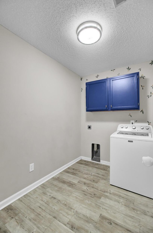 clothes washing area featuring washer / clothes dryer, light hardwood / wood-style floors, cabinets, and a textured ceiling