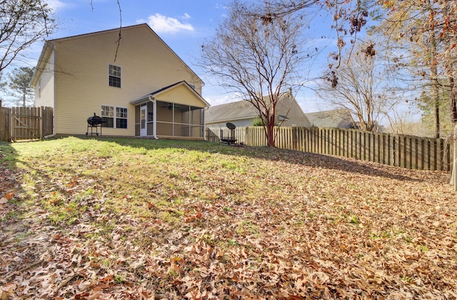 back of property featuring a sunroom and a lawn