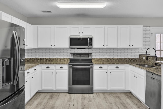 kitchen with dark stone countertops, stainless steel appliances, and white cabinets