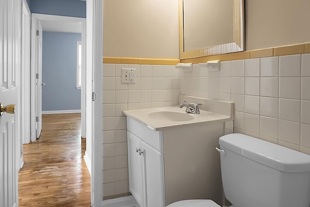 bathroom with vanity, toilet, wood-type flooring, and tile walls