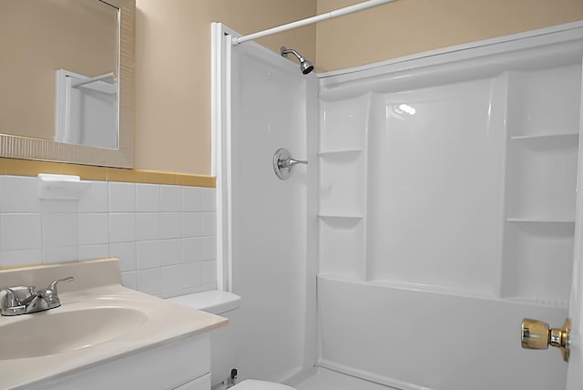 bathroom with vanity, toilet, tile walls, and a shower