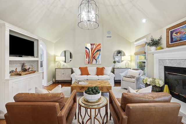 living room with light hardwood / wood-style flooring, lofted ceiling, a fireplace, and a chandelier