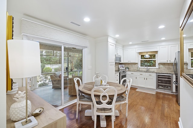 dining area featuring light hardwood / wood-style floors, sink, and beverage cooler