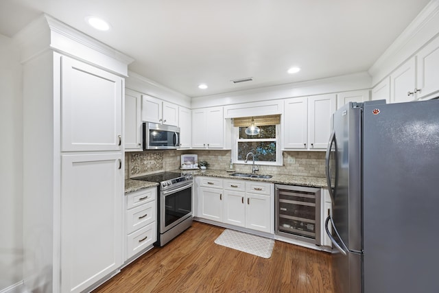 kitchen with light stone countertops, sink, beverage cooler, white cabinets, and appliances with stainless steel finishes