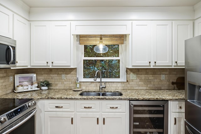 kitchen featuring appliances with stainless steel finishes, sink, white cabinets, wine cooler, and hanging light fixtures