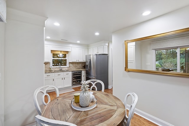 dining space featuring light hardwood / wood-style floors, wine cooler, and sink