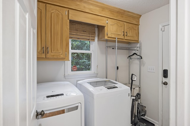 clothes washing area featuring cabinets, a textured ceiling, and separate washer and dryer